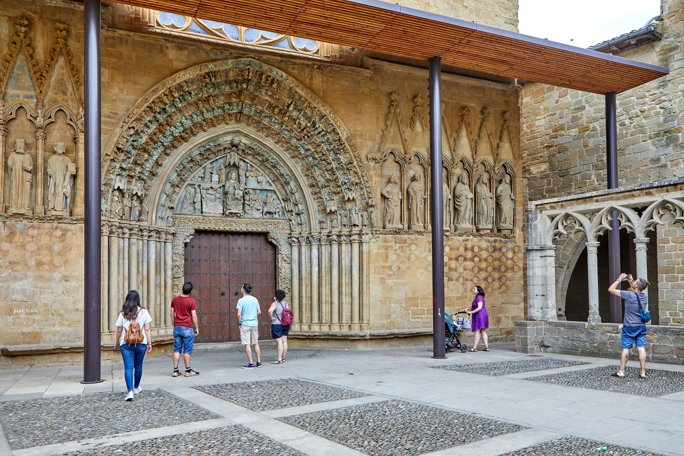 Several people observe the richly sculpted façade of the church of San Pedro de Olite